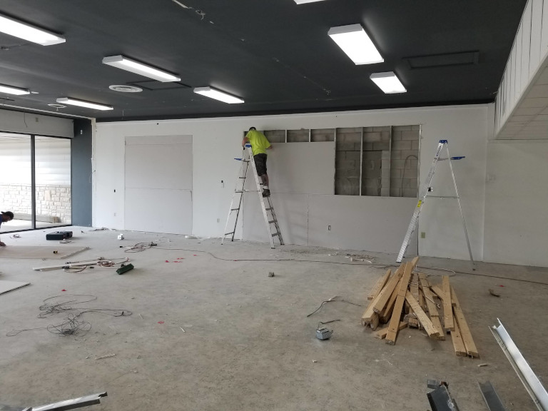 Interior finish work — drywall complete, storefront framing visible