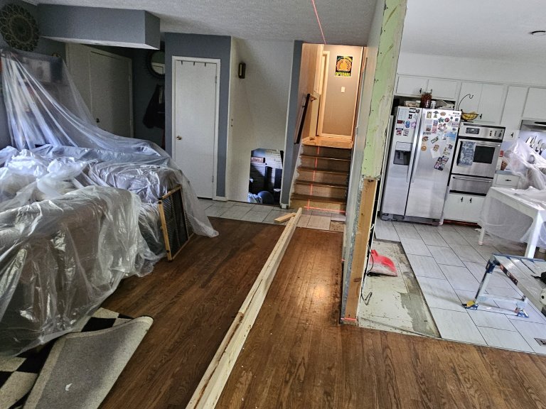 "Living room and kitchen divided by the bearing wall — laser level marking the shoring layout on the ceiling