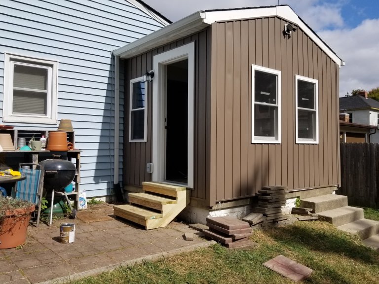 Finished exterior — board and batten siding with new entry and lighting